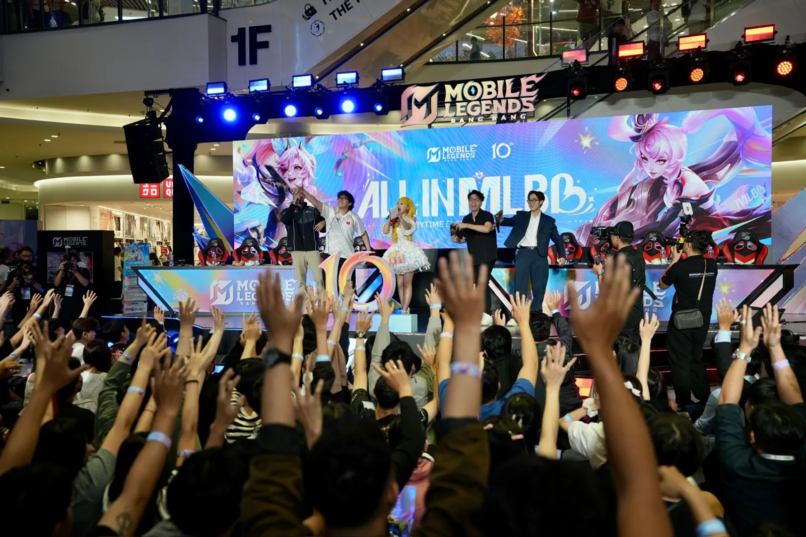 TK Nguyen on stage handing out GAM jerseys to a crowd with raised hands at MLBB's 10th anniversary