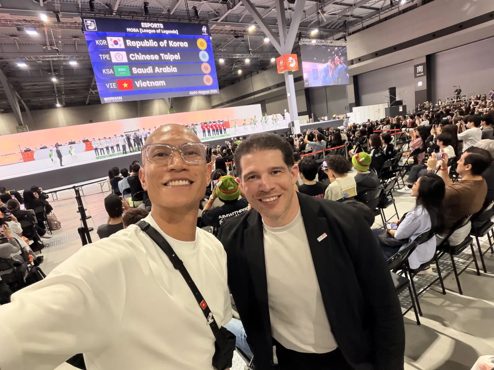 GAM Chairman Randy Dobson and TK Nguyen at Aichi Sky Expo, with the League of Legends medal board behind them